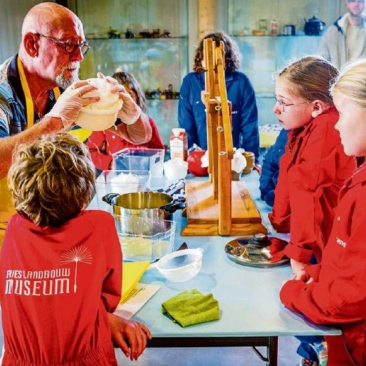 Vrijwilliger geeft uitleg aan kinderen tijdens de workshop kaasmaken