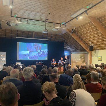 Familie Holtrop en H. van der Zwaag tijdens het startsymposium in een volle zaal