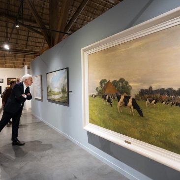 Minister Adema kijkt naar een schilderij in de nieuwe expositie