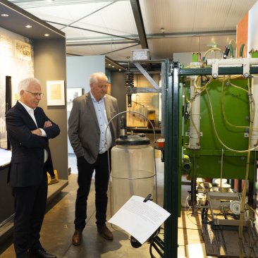Minister Adema en voorzitter Kooistra bij de eerste melkmachine, in het museum