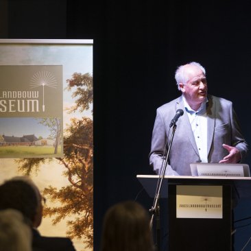 Voorzitter G. Kooistra spreekt de zaal toe tijdens de opening van de nieuwe expositie
