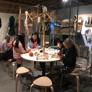 Jonge bezoekers aan de wol-tafel in de expositie