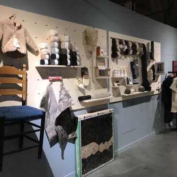 Muur met diverse wollen items in de expositie