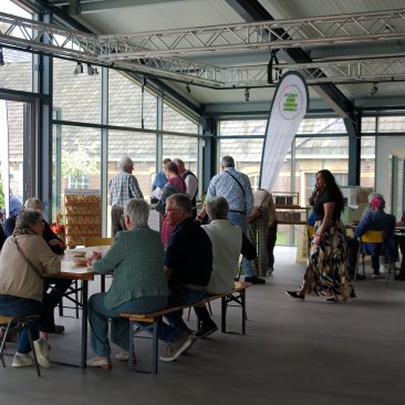 Mensen rond tafels in De Kas tijdens de open dag op 2 mei 2026, foto door Sytze Herder