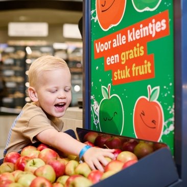 Een kind pakt een appel uit de bak "Voor alle kleintjes een gratis stuk fruit" van Lidl