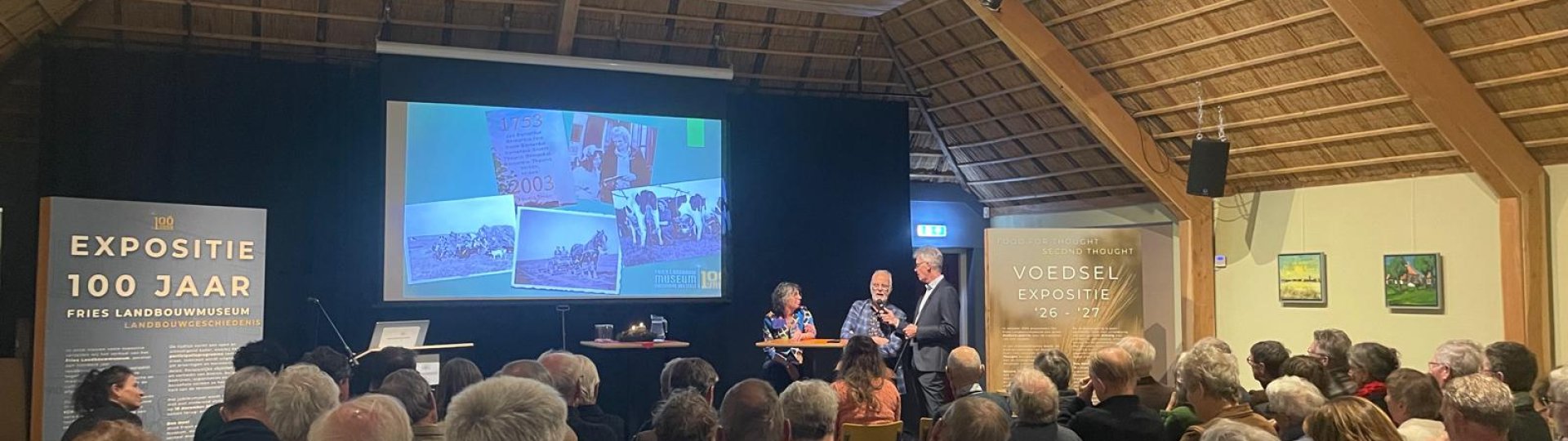 Familie Holtrop en H. van der Zwaag tijdens het startsymposium in een volle zaal