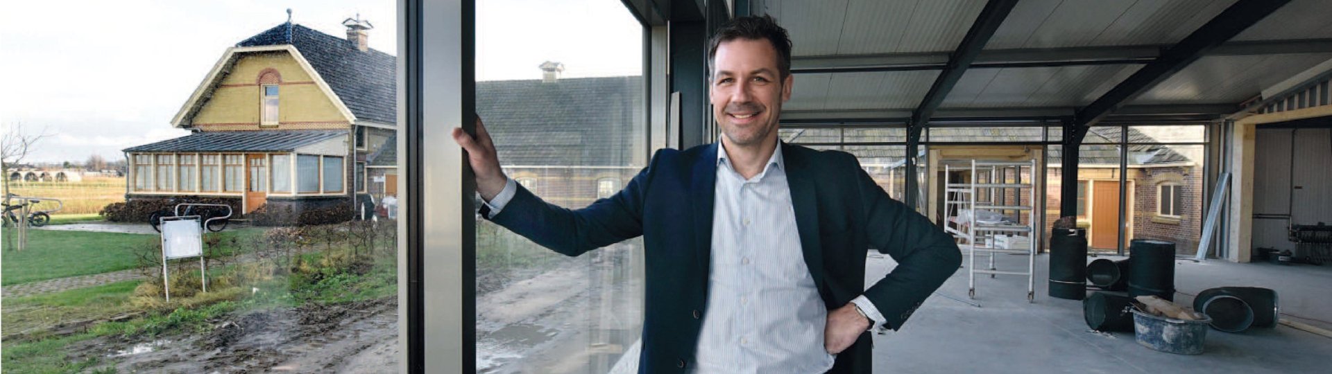 Foto uit het artikel in het Friesch Dagblad waar directeur Peter Wester in de nieuwbouw van het museum staat, met uitzicht op de boerderij