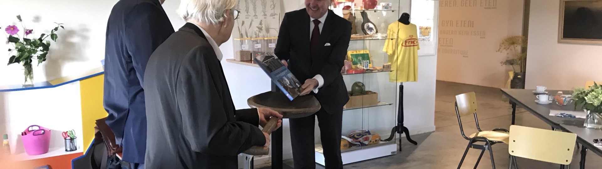 Overhandiging boek 'Cultureel erfgoed op it Fryske boerehiem' aan commissaris van de koning Arno Brok in de foyer van het Fries Landbouwmuseum