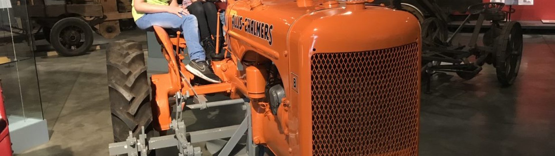 Twee kinderen zitten op de Allis-Chalmers trekker in het museum