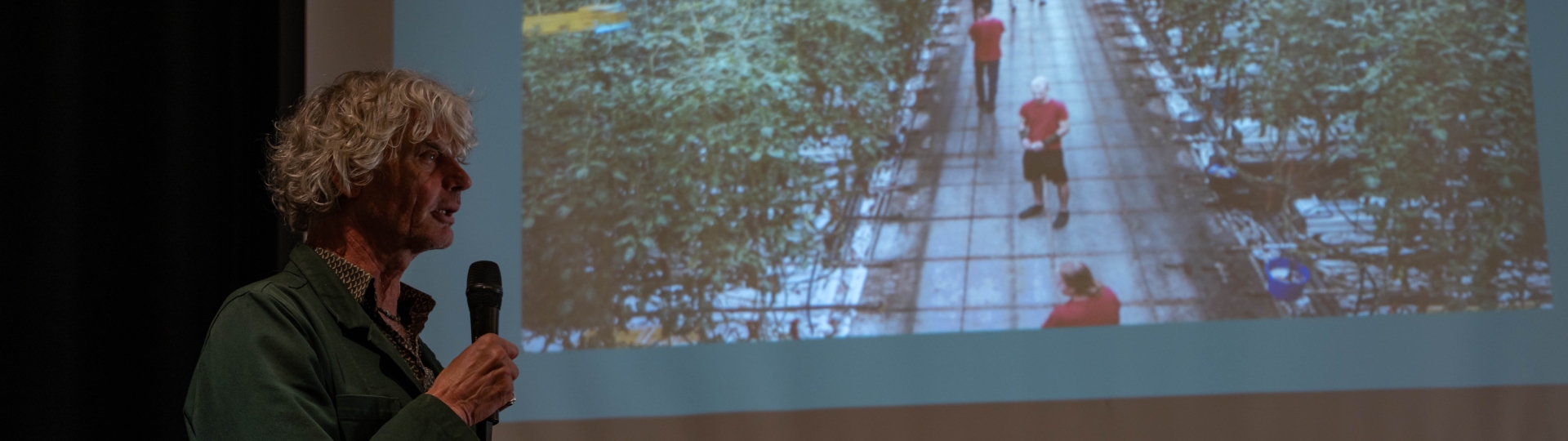 Kadir van Lohuizen staat voor een weergave van zijn foto van een tomatenkas
