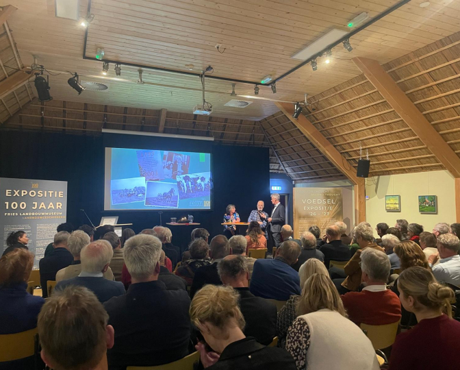 Familie Holtrop en H. van der Zwaag tijdens het startsymposium in een volle zaal