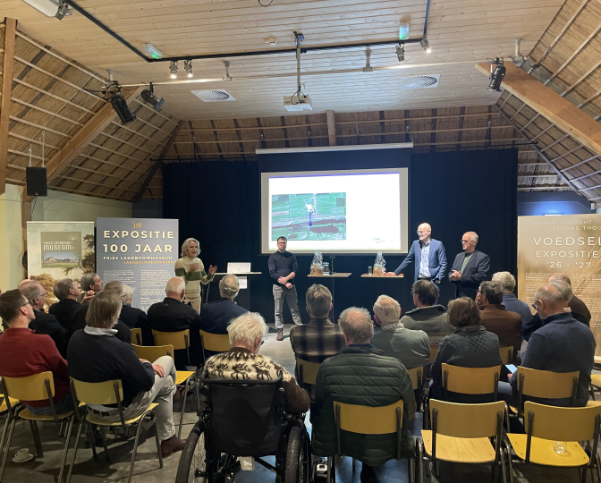 Debat "Niet alles kan overal, aldus Johan Remkes" in het Fries Landbouwmuseum. Voor het presentatiescherm staan sprekers leden van het Lânboukundich Wurkferbân
