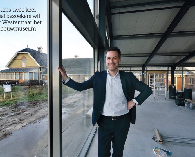 Foto uit het artikel in het Friesch Dagblad waar directeur Peter Wester in de nieuwbouw van het museum staat, met uitzicht op de boerderij