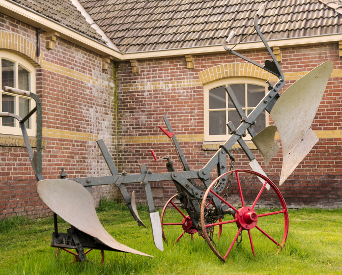 Kiepploeg op het terrein voor de monumentale boerderij