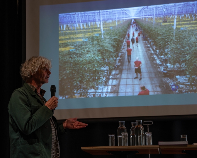 Kadir van Lohuizen staat voor een weergave van zijn foto van een tomatenkas